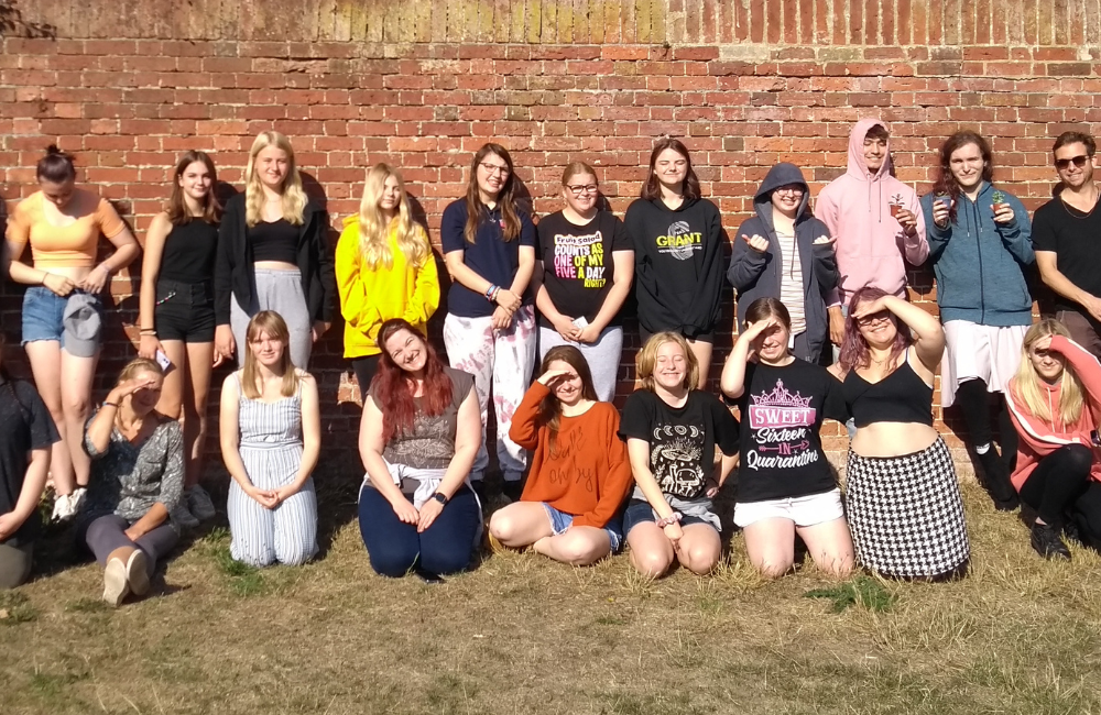 Group shot of lots of young people looking into the camera on a sunny day