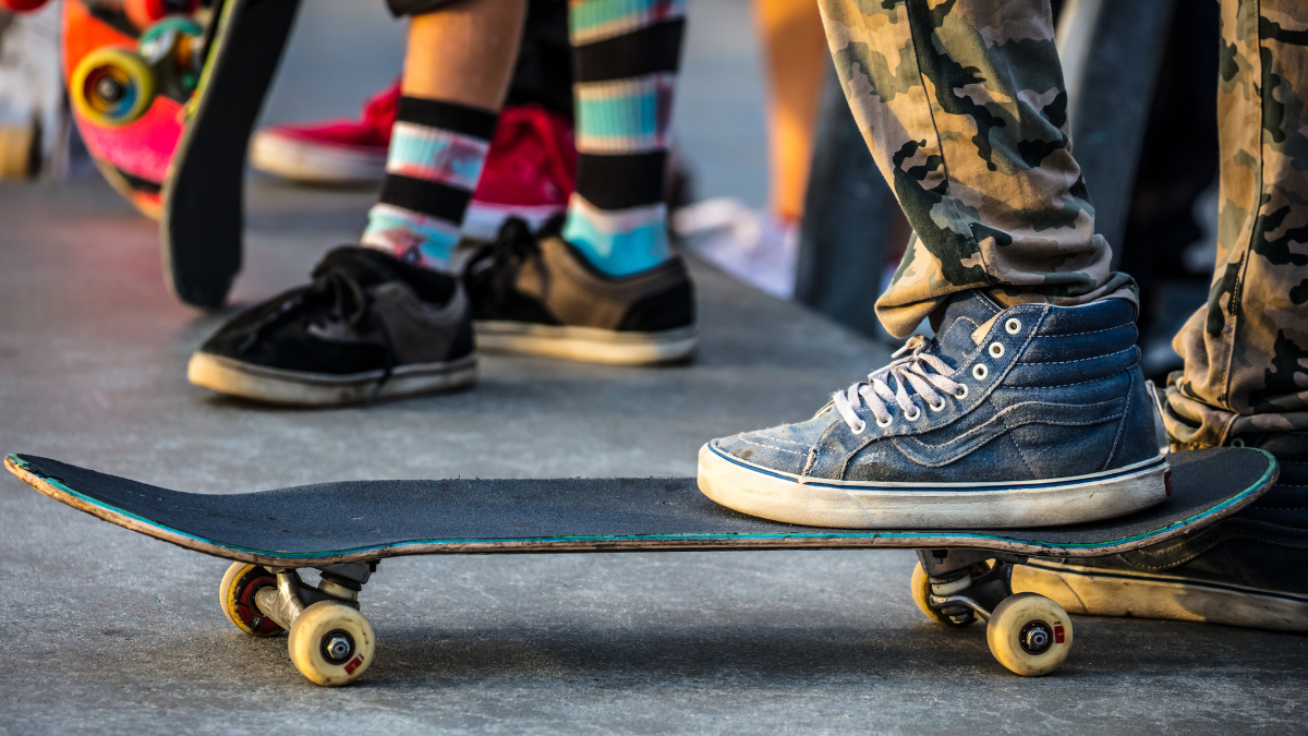A young person standing on a skateboard with other young people in the background
