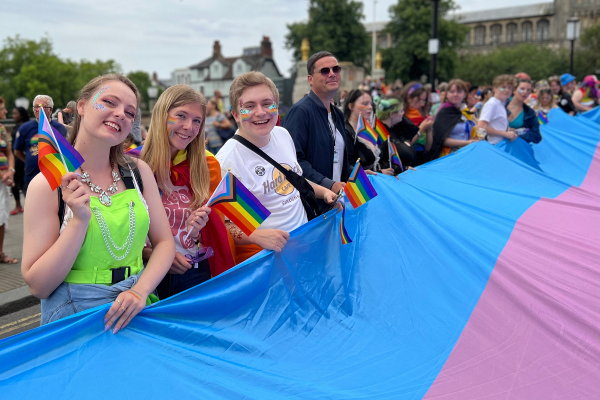 Young people carrying a large trans pride flag at Norwich Pride