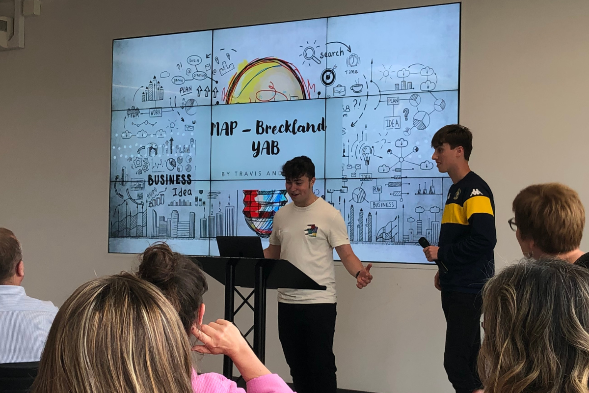 Two young people giving a presentation. Stood in front of a slide reading 'Breckland YAB'