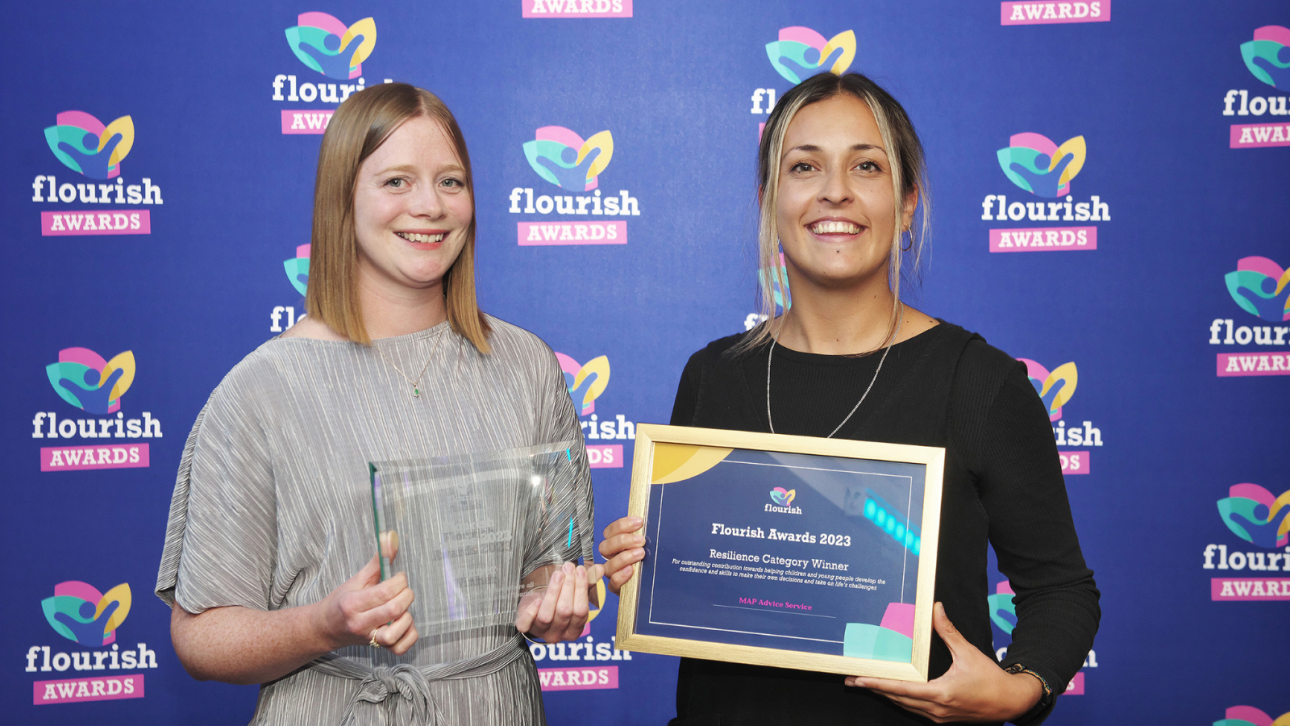 Two advice workers holding their flourish award, smiling at the camera