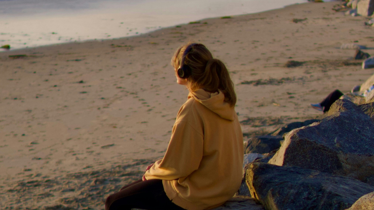 Young person on their own looking out to sea