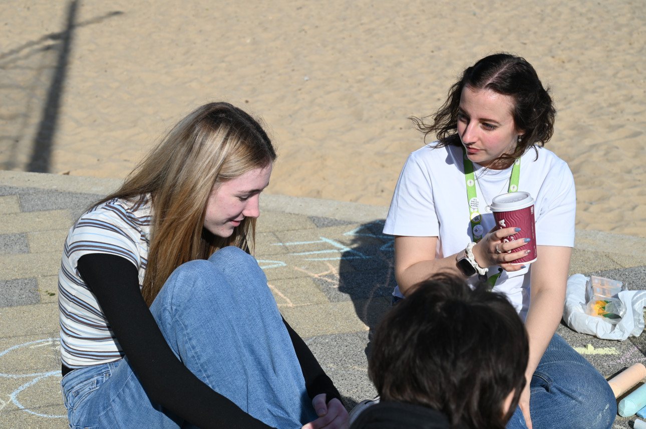 A staff member having a conversation with a young person at the beach