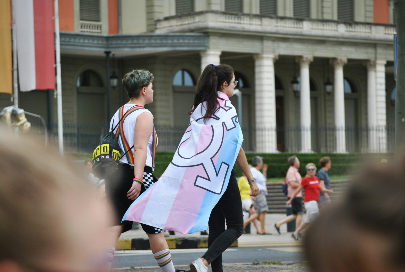 Two young people, one wearing a trans flag