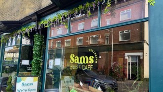 Image of Sam's cafe, a blue and glass shop front with tables outside