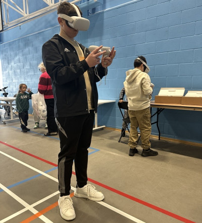 A young man with a virtual reality headset and nunchucks standing in a sports hall with blue tiles