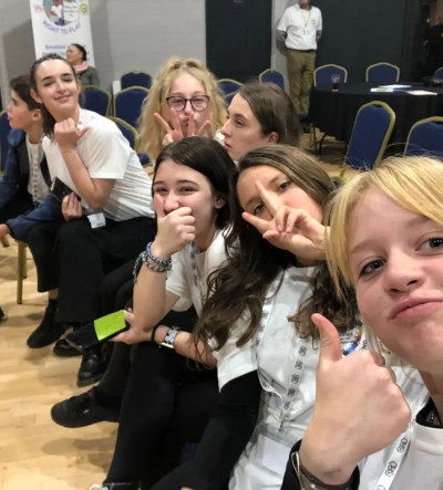 A group of six young people with their thumbs up in a selfie