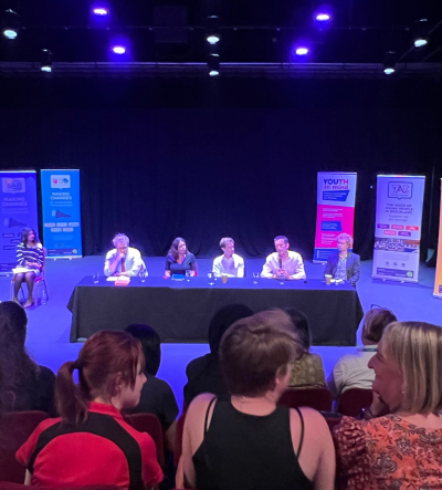 Five local election candidates on a panel in a busy theatre