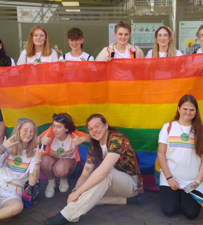 Young people in MAP tshirts holding a pride flag