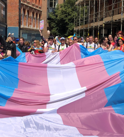 Trans flag being held by young people and other members of the public at Norwich Pride