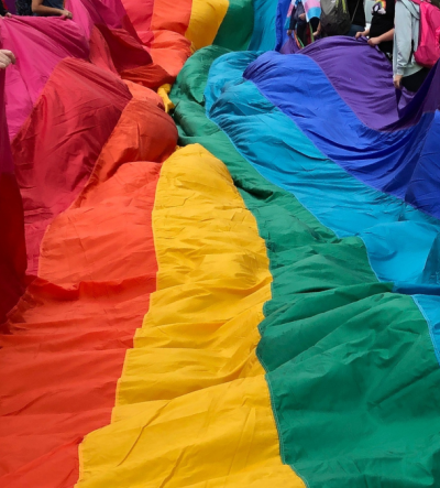 A giant rainbow flag being held by young people at Norwich Pride