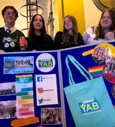 Young people and a youth worker stood behind a Norwich YAB stall