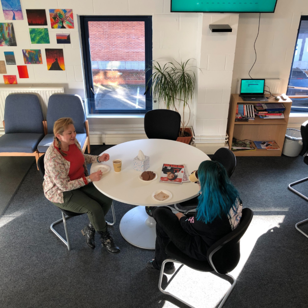 Young person and a youth worker sat around a table in the Risebrow Drop-In centre