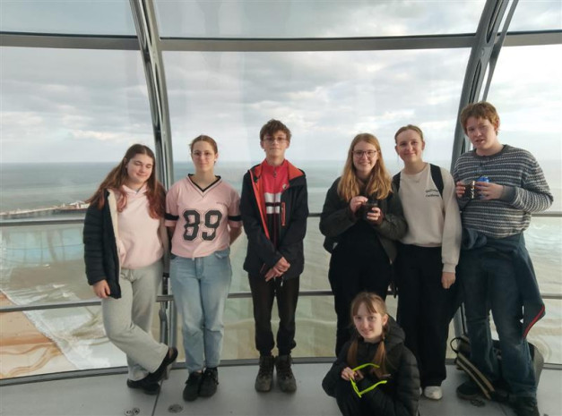 Seven young people, boys and girls, posing for a picture on the London Eye