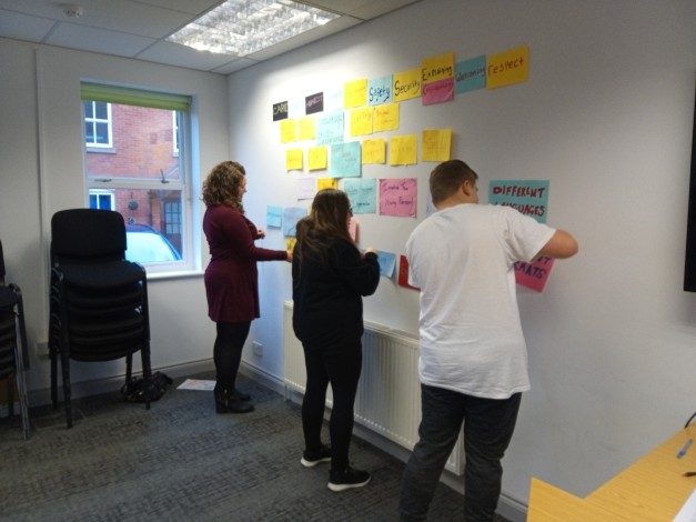 Young people and a youth worker putting colourful notes up on the wall