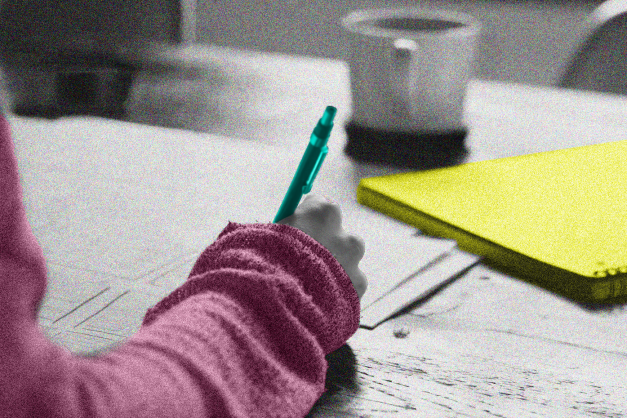 a girl's hand writing with a blue pen and a pink sleeve