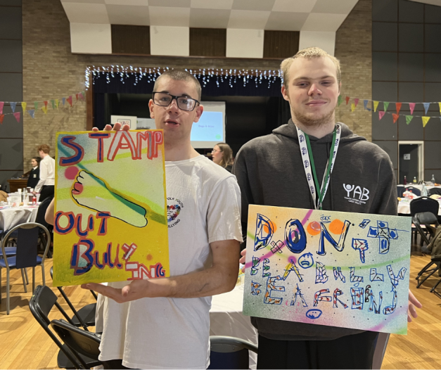 Two young people holding hand-painted anti-bullying signs