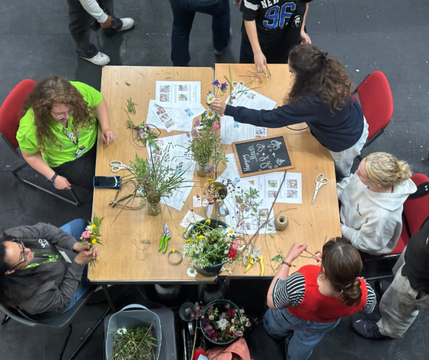 Young people and youth workers sat around a table crafting wall hangings