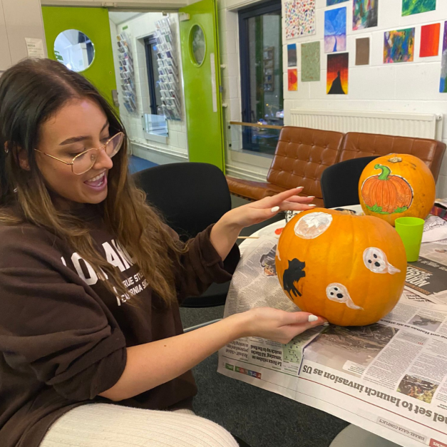 Young person at the Risebrow Centre sat with their freshly painted halloween pumpkins